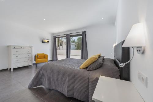 a white bedroom with a bed and a window at Villa Lali in Alcudia