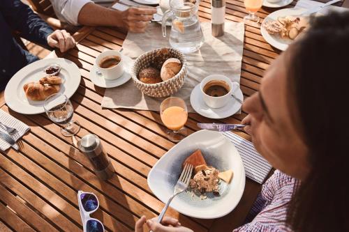 a group of people sitting at a wooden table eating food at ROBINSON JANDIA PLAYA - Adults only in Morro del Jable