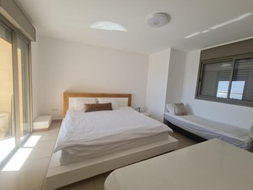 a white bedroom with a bed and a window at Top-Luxury Exclusive Аpt with Jacuzzi in front of the sea in Eilat