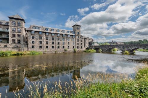 a large building next to a river with a bridge at The Riverside in Kendal