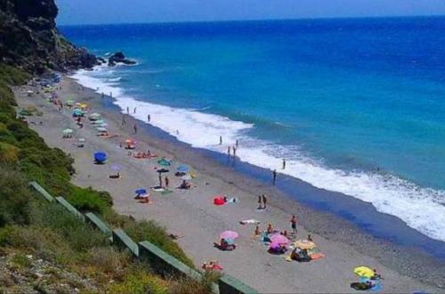 un gruppo di persone su una spiaggia con ombrelloni di Casa Mosaico Granada en el V de Lecrin a Nigüelas