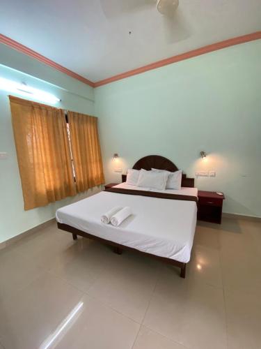 a bedroom with a large bed with white sheets at Packbag Comfort Bed & Breakfast in Kovalam