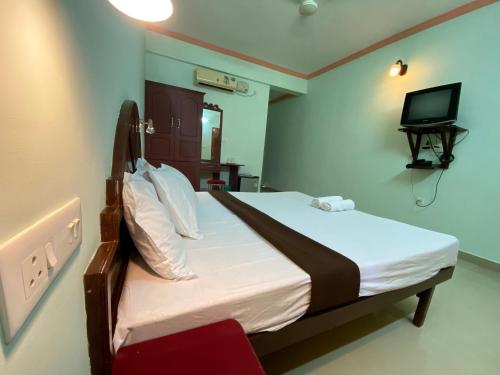 a bedroom with a bed and a television in it at Packbag Comfort Bed & Breakfast in Kovalam