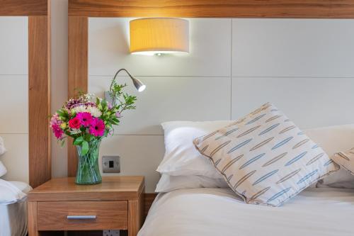 a vase of flowers on a night stand next to a bed at The Riverside in Kendal