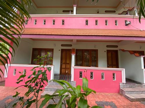 a pink and white house with pink doors at Packbag Comfort Bed & Breakfast in Kovalam