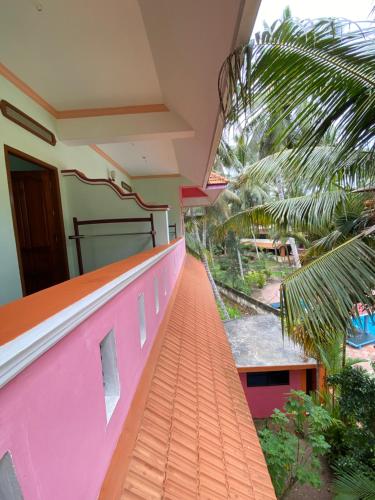 a balcony of a house with a pink wall at Packbag Comfort Bed & Breakfast in Kovalam