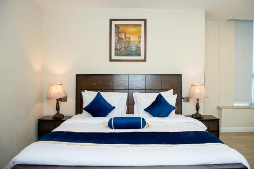 a bedroom with a large bed with blue pillows at Centaurus Hotel Suites in Islamabad