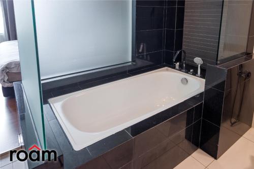 吉隆坡的住宿－Dua Sentral Kuala Lumpur by Roam，浴室设有浴缸,铺有黑色瓷砖。