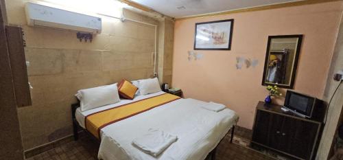 a small bedroom with a bed and a television at Nomadic Backpackers Hostel in Jaisalmer