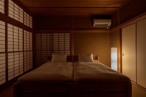 a bedroom with a bed with two pillows and a window at Suite Villa Atami Momoyama in Atami