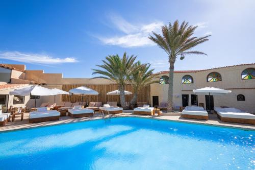 una grande piscina con sedie e ombrelloni di Hotel Playa Sur Tenerife a El Médano