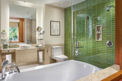 a bathroom with a tub and a toilet and green tiles at Sheraton Hua Hin Resort & Spa in Cha Am