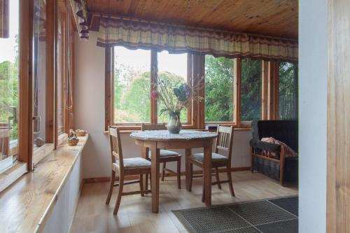 a dining room with a table and chairs in front of a window at Viesu māja Vanaturs in Roja