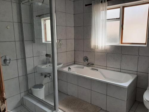 a bathroom with a tub and a sink and a toilet at Japie's Yard Self-Catering in Swakopmund