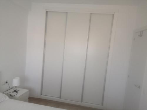 een slaapkamer met witte muren en een bed met een lamp bij Concordia in Roquetas de Mar