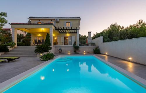 a swimming pool in front of a house at Villa Tatijana ZadarVillas in Kukljica