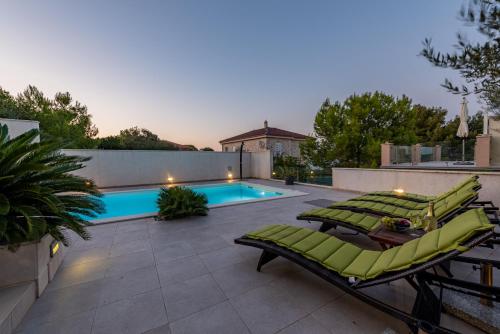 a patio with lounge chairs and a swimming pool at Villa Tatijana ZadarVillas in Kukljica