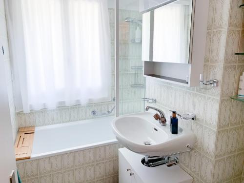 uma casa de banho branca com um lavatório e uma banheira em Bündapark em Davos