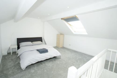 ein weißes Schlafzimmer mit einem Bett und einem Dachfenster in der Unterkunft Modern 4 bed house near city centre/Chester Zoo in Chester