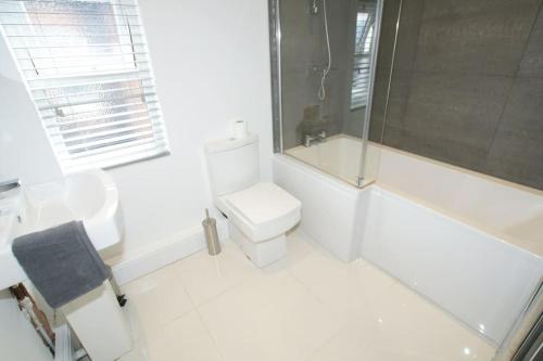 La salle de bains blanche est pourvue d'une douche et de toilettes. dans l'établissement Modern 4 bed house near city centre/Chester Zoo, à Chester