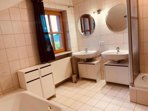 a bathroom with two sinks and a tub and a mirror at Adlerhorst in Thyrnau