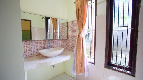 a bathroom with a sink and a mirror at Teges Inn Kuta in Kuta