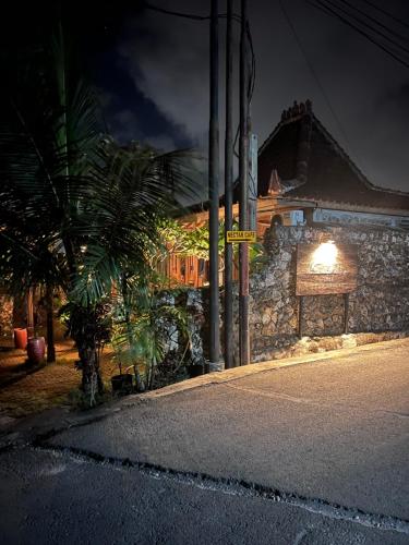 a stone building with a palm tree next to a street at PINOKKIO B&B Restaurant in Jimbaran
