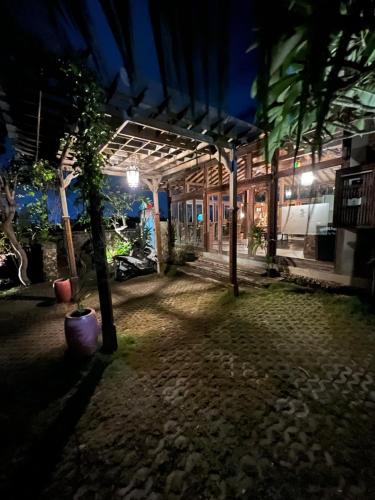 a night view of a patio with trees and a building at PINOKKIO B&B Restaurant in Jimbaran