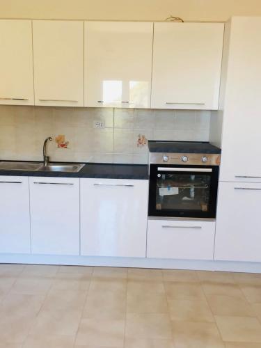 uma cozinha com armários brancos, um lavatório e um forno em ORO VERDE Apartments em Gagliano Castelferrato