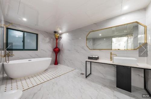 baño con bañera grande y espejo grande en Jamsil Tomgi Hotel en Seúl