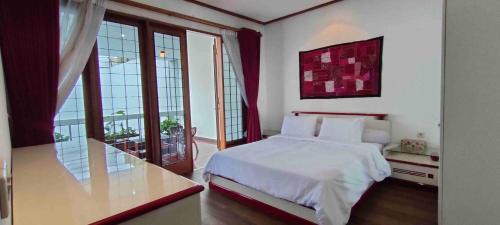 a bedroom with a white bed and large windows at Rumah Oma Lembang for Family & Friends in Lembang