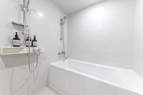 a white bathroom with a shower and a bath tub at Busan Seomyeon Broa Hotel in Busan