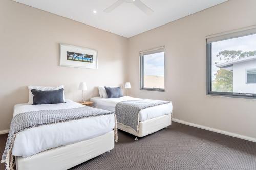 two beds in a white room with two windows at Dunn Bay Apartment 5 I Private Properties in Dunsborough