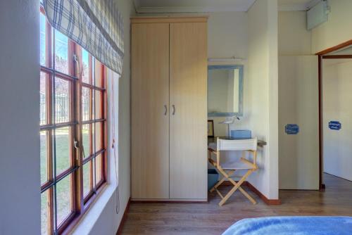 a room with a bedroom with a desk and windows at Mrs Simpson in Dullstroom
