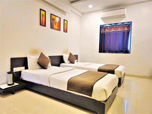 two beds in a hotel room with a window at The Grand Rio in Rajkot