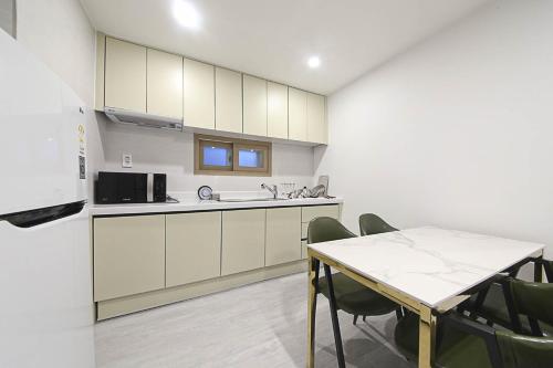 a kitchen with white cabinets and a table with chairs at Busan Seomyeon Broa Hotel in Busan