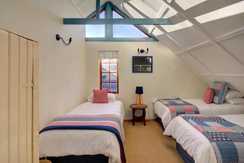a attic room with three beds and a window at Mrs Simpson in Dullstroom