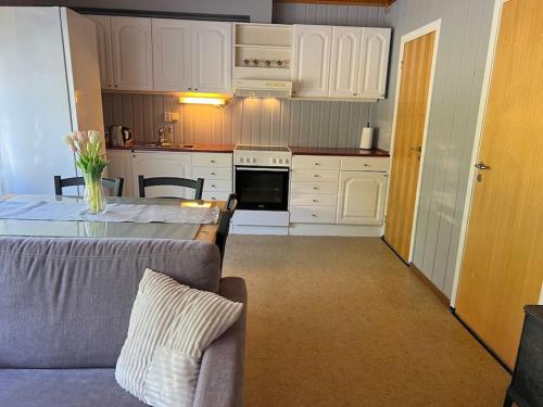 a kitchen with white cabinets and a table with a couch at Apartment-A near Etne-Odda in Etnesjøen