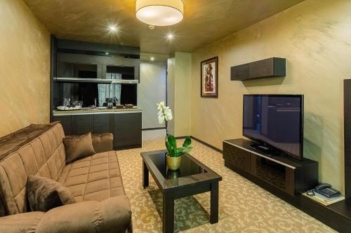 a living room with a couch and a tv at Royal Spa Hotel in Velingrad