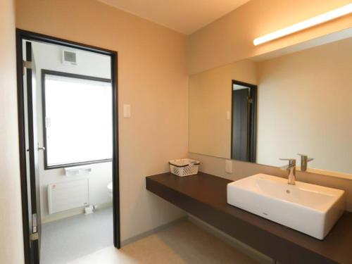 y baño con lavabo blanco y espejo. en Kamuy Rera en Kushiro