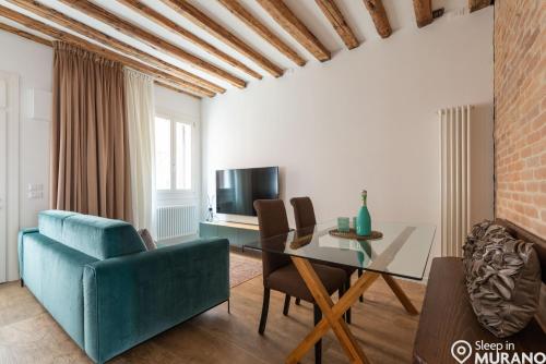 a living room with a table and a blue couch at MURANO Place - MISTRO House in Murano