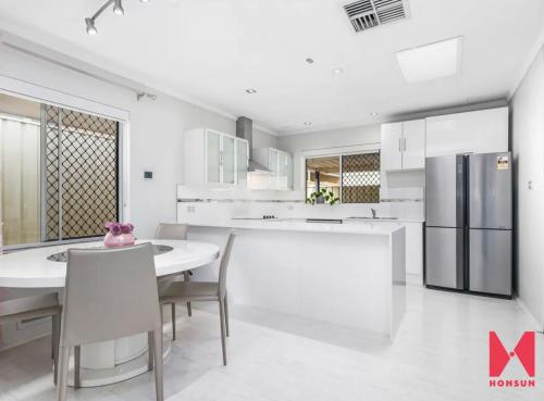 cocina blanca con mesa y nevera en Leisurehome en Perth