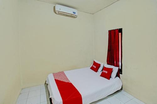 a bedroom with a bed and a red window at OYO Life 93058 Kos Subur in Tanjung