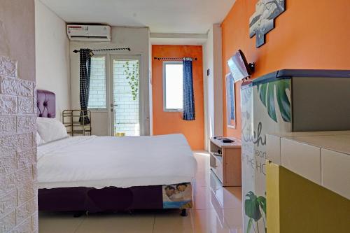 een slaapkamer met een bed en een oranje muur bij OYO Life 92898 Apartement Buah Batu Park By Yuliam in Bandung