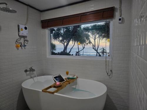 a white tub in a bathroom with a window at Lanta Nice Beach Resort - SHA Extra Plus in Ko Lanta