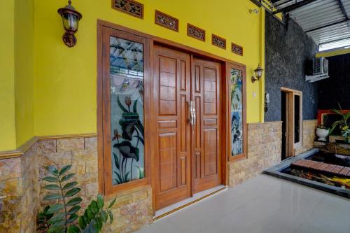 een grote houten deur in een gele muur bij OYO Life 92840 Wisma Morricco in Jombang