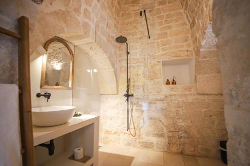 ein Bad mit einem Waschbecken und einer Dusche in der Unterkunft Trulli Dimore - Tortorella in Monopoli