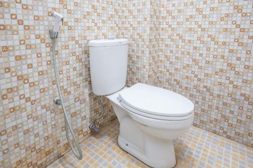 La salle de bains est pourvue de toilettes blanches et d'un mur carrelé. dans l'établissement OYO Life 92803 Penginapan Purnama, à Kayuagung