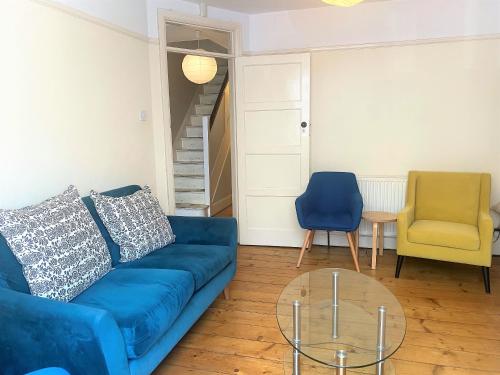 un soggiorno con divano blu e tavolo in vetro di Colourful vintage-styled home in lovely Southville a Bristol