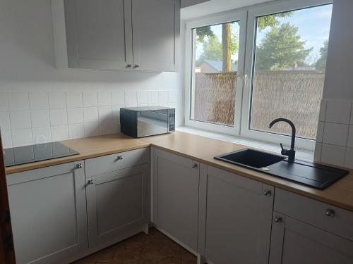 a kitchen with white cabinets and a sink and a window at Kraken-pokoje gościnne in Krynica Morska